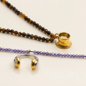Detail of beaded necklaces with a gold coffee cup pendant and silver headphone charm