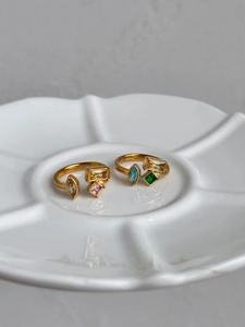 Detail of 18k gold plated ring with colorful geometric zircons on white petal dish