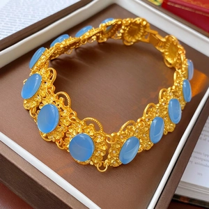 Vintage style gold bracelet with blue oval gemstones and intricate floral engraving