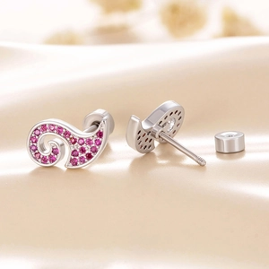 Silver wave-shaped screw back earrings with pink pavé crystals on beige silk fabric