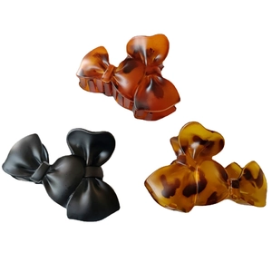 Three oversized matte bow hair claws in tortoiseshell and black on white background