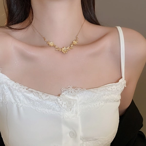 Close-up of golden leaf pendant necklace with zircon inlay on female collarbone