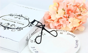 Close-up of a premium black metal eyelash curler on a vintage aesthetic background