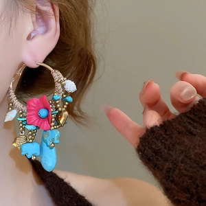 Detail view of bohemian hoop earring with turquoise stone, resin flower and woven cord