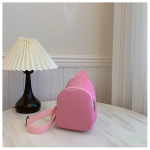 Detailed view of pink nylon kids crossbody bag with silver zipper on marble table