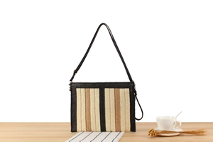 Close-up of hand-woven paper rope bag with striped pattern and black leather trim