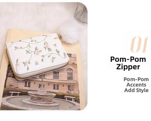 Detail of white PU leather wallet with floral embroidery and large pom-pom zipper charm