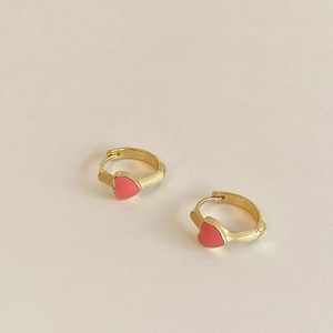 Detailed macro view of gold-plated copper earrings with pink enamel heart charms