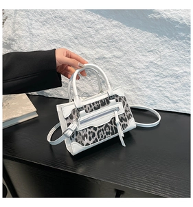 Detalle de la textura de leopardo y la cremallera con borla en este bolso de piel blanca