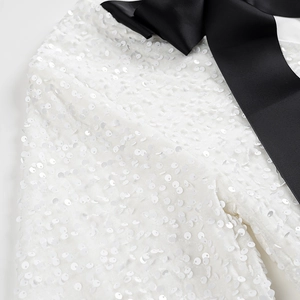 Vue détaillée du tissu à paillettes blanches avec ruban noir contrasté sur la robe