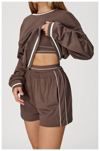 Detail of three-piece brown sweatshirt set with white stripe ribbing on cuffs and hemline