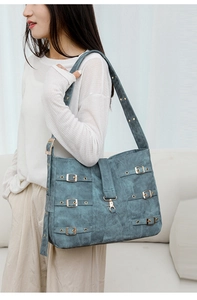 Close-up of vintage teal tote bag featuring metallic buckle straps and suede-like texture