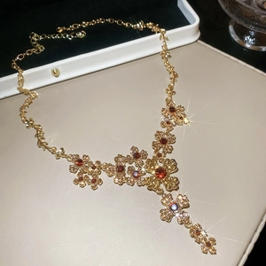 Detailed view of vintage gold necklace with crystal cross pendant and red gemstones