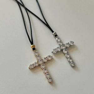 Detailed shot of cross pendants with zircon pavé on black cords in gold and silver