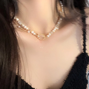 Close-up of double-layer necklace with faux pearls and golden chain on neck