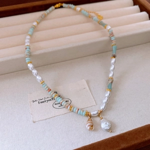 Detail of freshwater pearl and seashell pendant necklace on velvet jewelry display