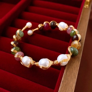 Detail of gold plated wrap bracelet with white freshwater pearls and colorful natural stones