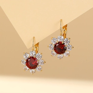 Macro shot of gold flower earrings with a red gemstone and sparkling white crystals