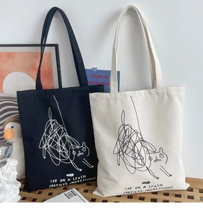 Artistic display of black and white canvas tote bags with cute cat doodle designs