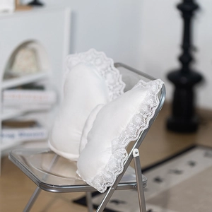 Detail of two white heart-shaped plush pillows with elegant lace embroidery edges