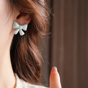 Close-up of matte acrylic bow stud earring on model with French vintage aesthetic