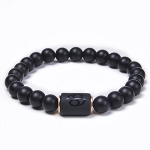 Close-up of matte black agate beads and rose gold Cancer zodiac charm on the bracelet