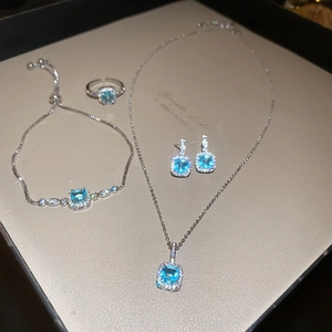 Close-up of light blue halo square gemstone jewelry set with necklace, ring, and bracelet