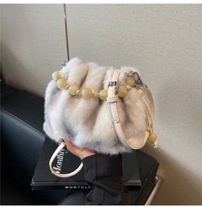 Detail of light gray faux fur bucket bag featuring a decorative beaded handle and strap