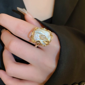 Gros plan détaillé d'une bague papillon dorée avec perle baroque et détails de feuilles