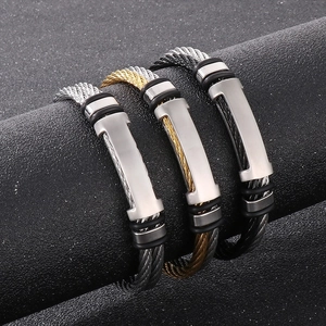 Close-up of woven stainless steel wire bracelets in silver, gold, and black with metal plates