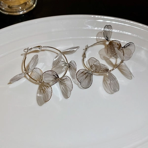 Détail macro de boucles d'oreilles ailes de papillon argentées sur assiette blanche