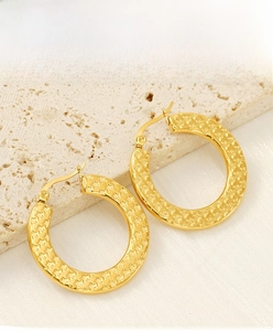 Macro shot of gold stainless steel hoop earrings with hammered texture and star pattern