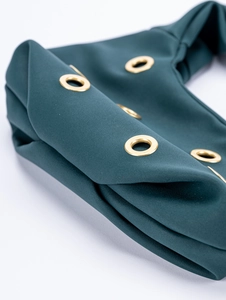 Detail of dark green suede fabric with gold metal grommets and pleated texture