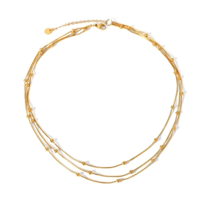 Detail view of a triple-layered gold stainless steel bead chain necklace with lobster clasp