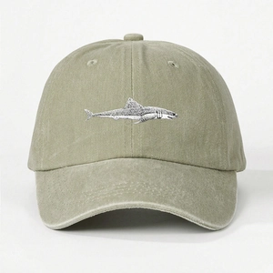 Close-up of detailed shark embroidery on washed olive green cotton baseball cap