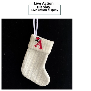 Macro view of white cable knit Christmas stocking with embroidered red letter A and Santa hat