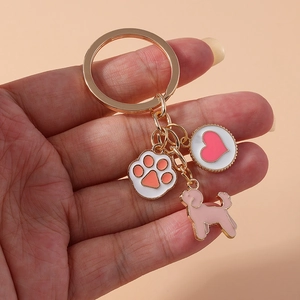 Golden keychain featuring pink cat paw, heart charm, and poodle pendant on gold ring