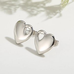 Polished silver heart-shaped stainless steel earrings with cutout design on a white surface