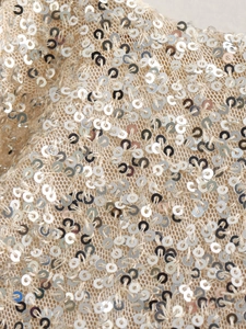 Macro shot of silver sequins on champagne knit mesh fabric of a bodycon dress