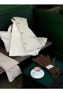 Detailed close-up of brown knit wool gloves with a quality woven label on a wooden stool