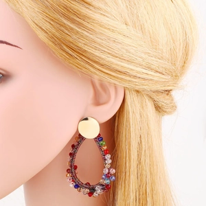 Macro detail of bohemian colorful beaded teardrop earrings on golden studs