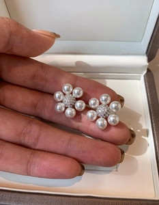 Gros plan de boucles d'oreilles fleurs en perles avec zircon tenu sur le doigt