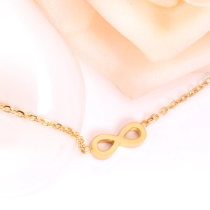 Macro shot of gold infinity symbol pendant on a delicate stainless steel chain necklace