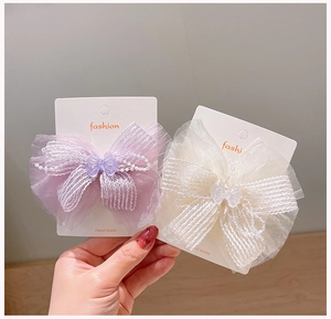 Detail of purple and cream chiffon bow hair clips with delicate pearl bead accents