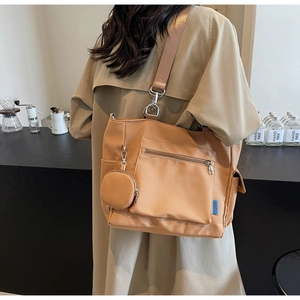 Detail of khaki nylon tote bag featuring wide strap, metal clasp, and small coin purse