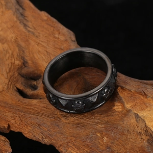 Macro shot of black titanium skull relief ring on rustic wood background for men