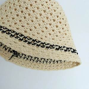 Detailed close-up of intricate beige crochet straw hat with black woven stripe texture