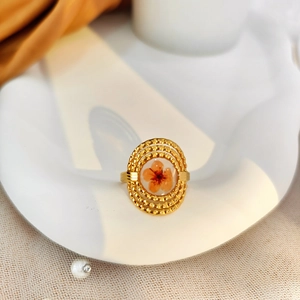 Detailed shot of a vintage gold plated open ring with orange floral resin inlay