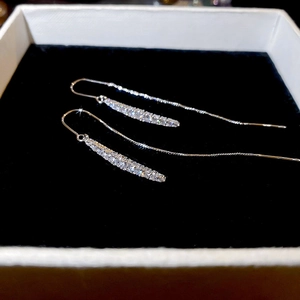 Detail of silver drop chain earrings with pavé zircon stones on a jewelry box background