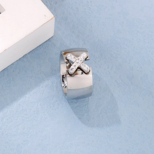 Macro detail of silver stainless steel wide band ring with crisscross X-shape zircon pavé